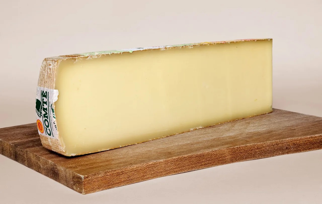 A long slab of Comté cheese on a wooden board