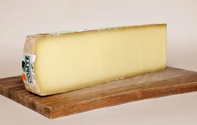 A long slab of Comté cheese on a wooden board