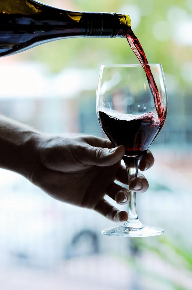 Red wine being poured into a glass outdoors
