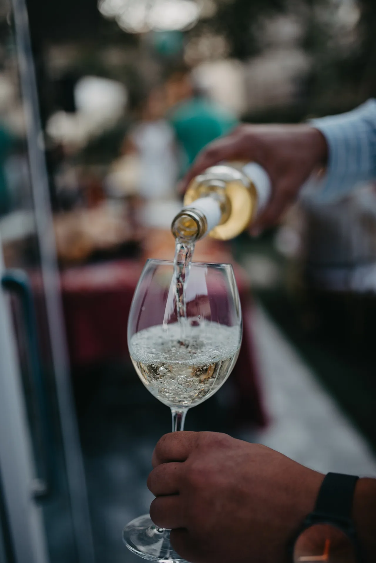 White wine being poured into a glass in a garden