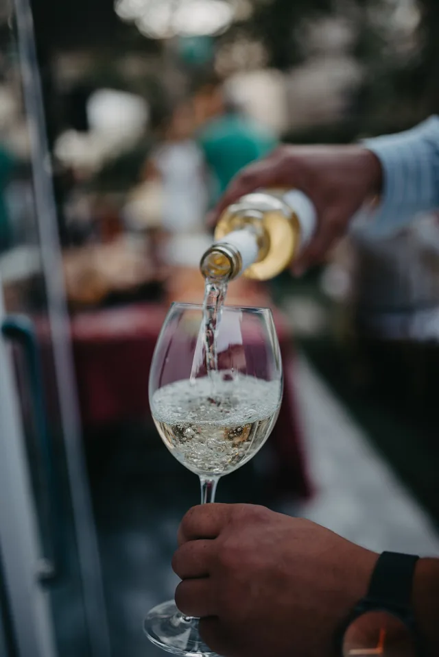 White wine being poured into a glass in a garden