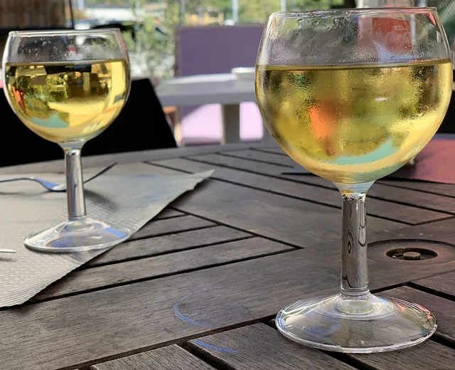 Two glasses of white wine on a wooden terrace table